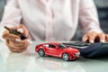 woman uses a calculator while signing a contract document for car insurance. Royalty Free Stock Photo