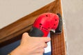 A woman uses a sanding machine to work the wood of a door