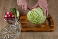 A woman uses a kitchen knife to cut fresh white cabbage on a wooden cutting board. Close-up female hands chopping Royalty Free Stock Photo