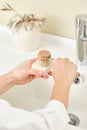 Woman uses in the kitchen wooden dishwashing brush and a piece of environmentally friendly detergent.