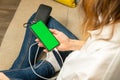 The woman uses a mobile phone, a smartphone with green screen, charged from the power bank Royalty Free Stock Photo