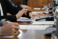 Woman uses a mobile phone - a smartphone - while sitting at a table with colleagues. A meeting or negotiation. Business at a call Royalty Free Stock Photo