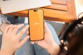 A woman uses the Payoneer application on her iPhone while sitting at a table in a cafe