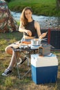 Woman uses solar panel outdoors on camping to generate electricity for cooking Royalty Free Stock Photo