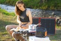 Woman uses solar panel outdoors on camping to generate electricity for cooking Royalty Free Stock Photo