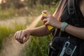 Woman using anti mosquito spray outdoors at hiking trip. Close-up of young female backpacker tourist applying bug spray on hands Royalty Free Stock Photo