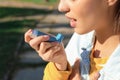 Woman using asthma inhaler outdoors Royalty Free Stock Photo