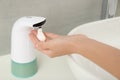 Woman using automatic soap dispenser in bathroom Royalty Free Stock Photo