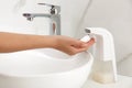 Woman using automatic soap dispenser in bathroom Royalty Free Stock Photo