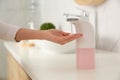 Woman using automatic soap dispenser in bathroom, closeup Royalty Free Stock Photo