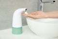 Woman using automatic soap dispenser in bathroom