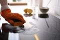 Woman using baking soda to clean electric cooktop indoors, closeup. Wrong detergent for such surfaces