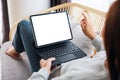A woman using black tablet pc with blank desktop white screen as a computer pc while lying on a sofa at home Royalty Free Stock Photo