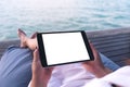 Woman using black tablet pc with blank white desktop screen while sitting by the sea Royalty Free Stock Photo