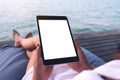 Woman using black tablet pc with blank white desktop screen while sitting by the sea Royalty Free Stock Photo