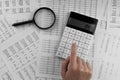 Woman using a calculatorwith magnifyingglass and financial statement lying on the table