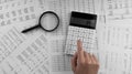 Woman using a calculatorwith magnifyingglass and financial statement lying on the table Royalty Free Stock Photo