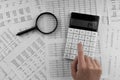 Woman using a calculatorwith magnifyingglass and financial statement lying on the table Royalty Free Stock Photo