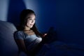 Woman using cellphone on bed at night Royalty Free Stock Photo