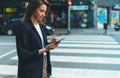 Woman using cellphone and crossing street, young hipster girl in business wear holding smartphone gadget using for online booking Royalty Free Stock Photo