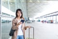 Woman using cellphone with her luggage in airport Royalty Free Stock Photo