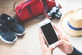 Woman using cellphone with travel preparations on wood floor