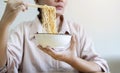 Woman using chopsticks eating instant ramen, noodles, cheap food and no money for dinner Royalty Free Stock Photo