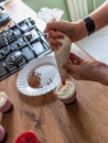 Woman using confectioners bag for putting whipped cream of white color and decorating Birthday cake at home