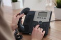 Woman using desktop telephone at wooden table in office, closeup. Hotline service Royalty Free Stock Photo