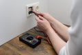 woman using digital multimeter to check current voltage in electric socket Royalty Free Stock Photo