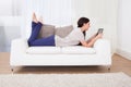 Woman using digital tablet on sofa Royalty Free Stock Photo