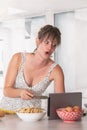 Woman using digital tablet with stunned expression in kitchen Royalty Free Stock Photo
