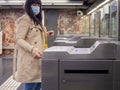 Woman using face mask for covid inserting a subway ticket to enter a metro station. Royalty Free Stock Photo