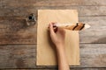 Woman using feather pen to write with ink on parchment at wooden table, top view Royalty Free Stock Photo