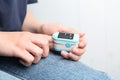 Woman using fingertip pulse oximeter on background, closeup