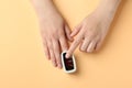 Woman using fingertip pulse oximeter on orange background, top view