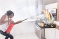 Woman Using Fire Extinguisher To Stop Fire Coming From Oven Royalty Free Stock Photo