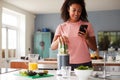 Woman Using Fitness Tracker To Count Calories For Post Workout Juice Drink He Is Making Royalty Free Stock Photo