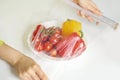 Woman using food film for food storage on a white table. Roll of transparent polyethylene food film for packing products