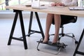 Woman using footrest while working on computer in office