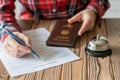 Woman using Germany passport filling hotel reservation form in the hotel. Silver vintage bell on wooden rustic reception desk. Royalty Free Stock Photo