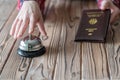 Woman using Germany passport for registration in the hotel. Silver vintage bell on wooden rustic reception desk. Hotel service. Royalty Free Stock Photo