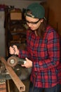 Woman using grinder on the metal pole in the small workshop