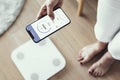 Woman using health tracking on her phone by the weighing scale innovative technology