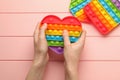 Woman using heart shaped pop it fidget toy at pink wooden table, top view Royalty Free Stock Photo