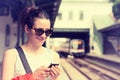 Woman using her cell phone on subway platform, checking train schedule Royalty Free Stock Photo