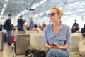 Woman using her cell phone while waiting to board a plane at departure gates at international airport. Royalty Free Stock Photo