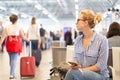 Woman using her cell phone while waiting to board a plane at departure gates at international airport. Royalty Free Stock Photo