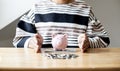 A woman is using her hand to protect the piggy bank and money on the desk. Royalty Free Stock Photo