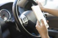 Woman using her smartphone open mobile application navigation or gps while driving. Blurred car interior background. Viewing Royalty Free Stock Photo